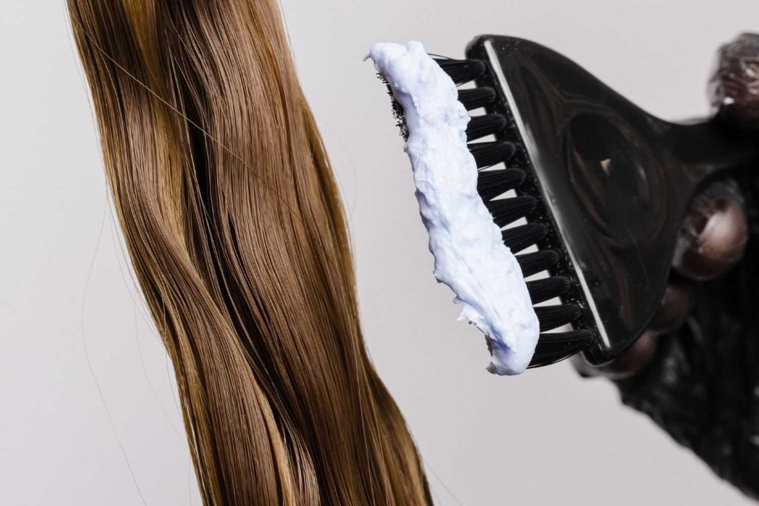 Close-up of hair being dyed with a brush applying white dye.