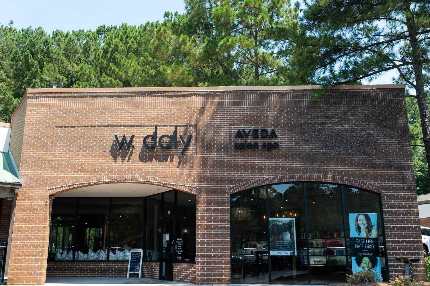 Exterior of W. Daly Aveda salon and spa with brick facade and large glass windows.