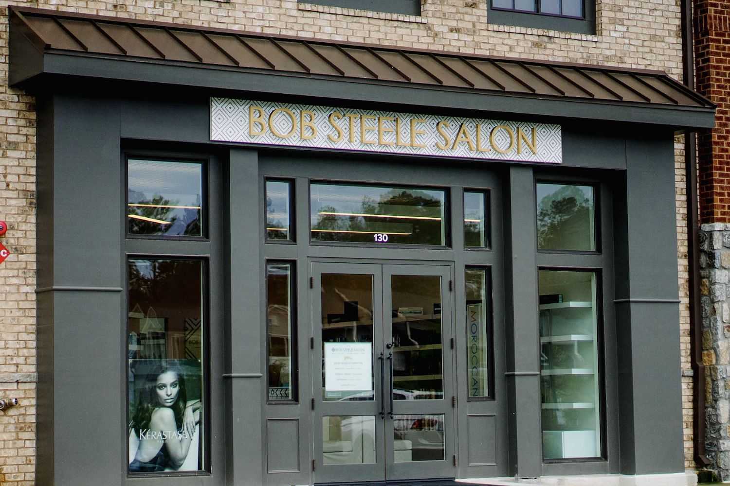 Entrance of a modern salon named "Bobshelle Salon" with large windows and a poster on the left side.